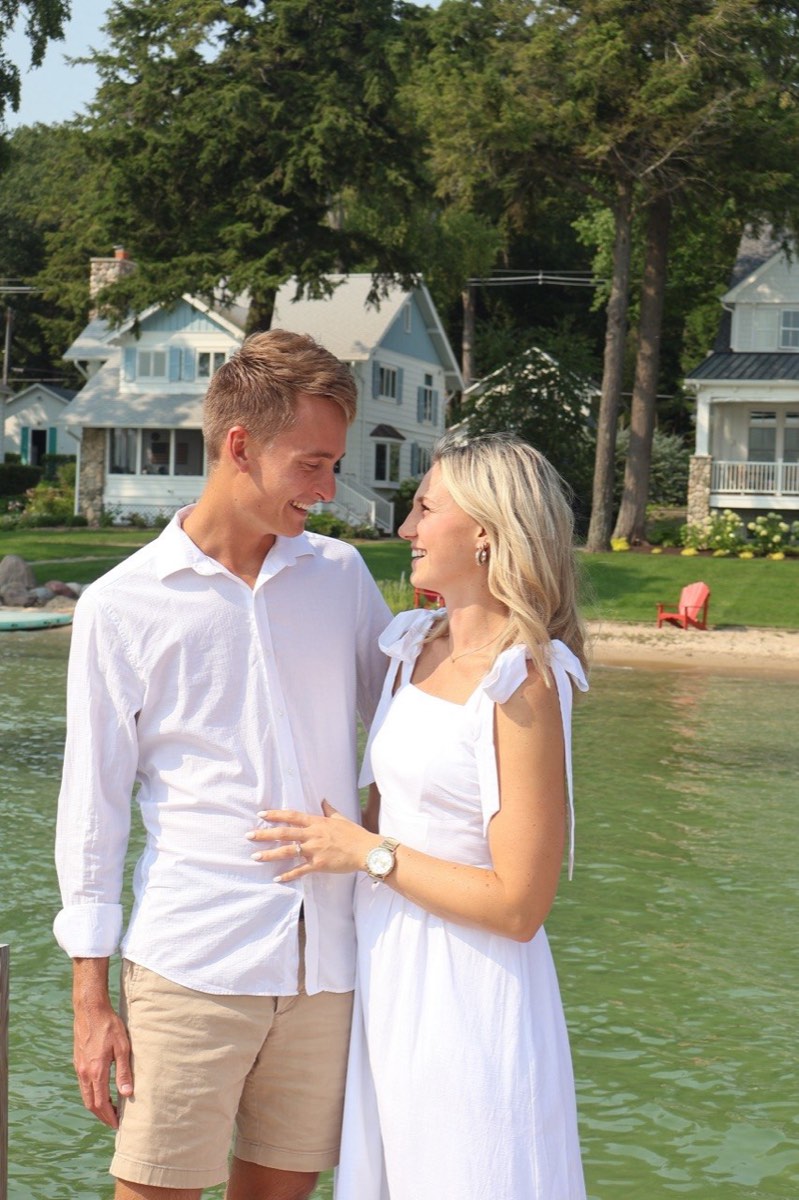 Tucker and Syd smiling at each other beside green lake water