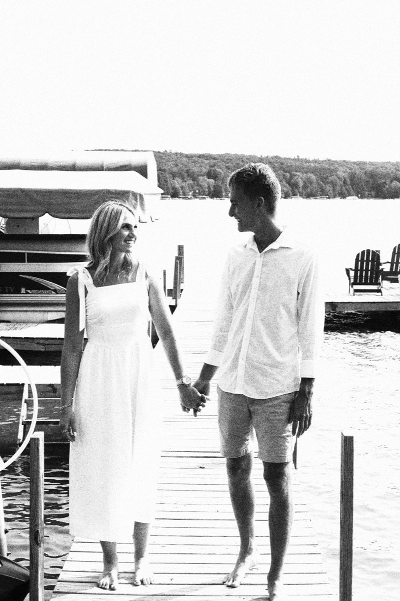 Tucker and Syd walking hand in hand along a dock at Walloon Lake