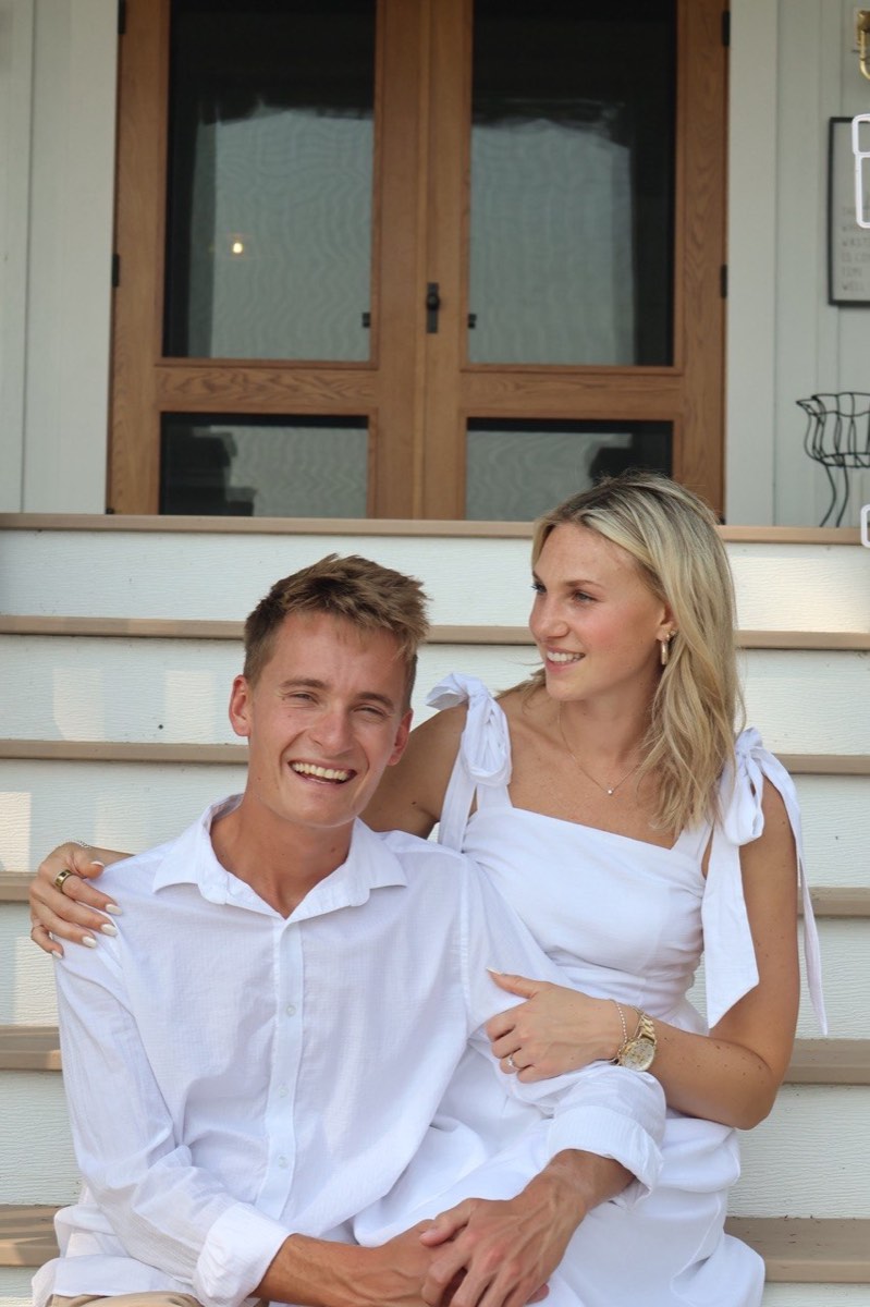 Tucker laughing as Syd sits beside him on the steps